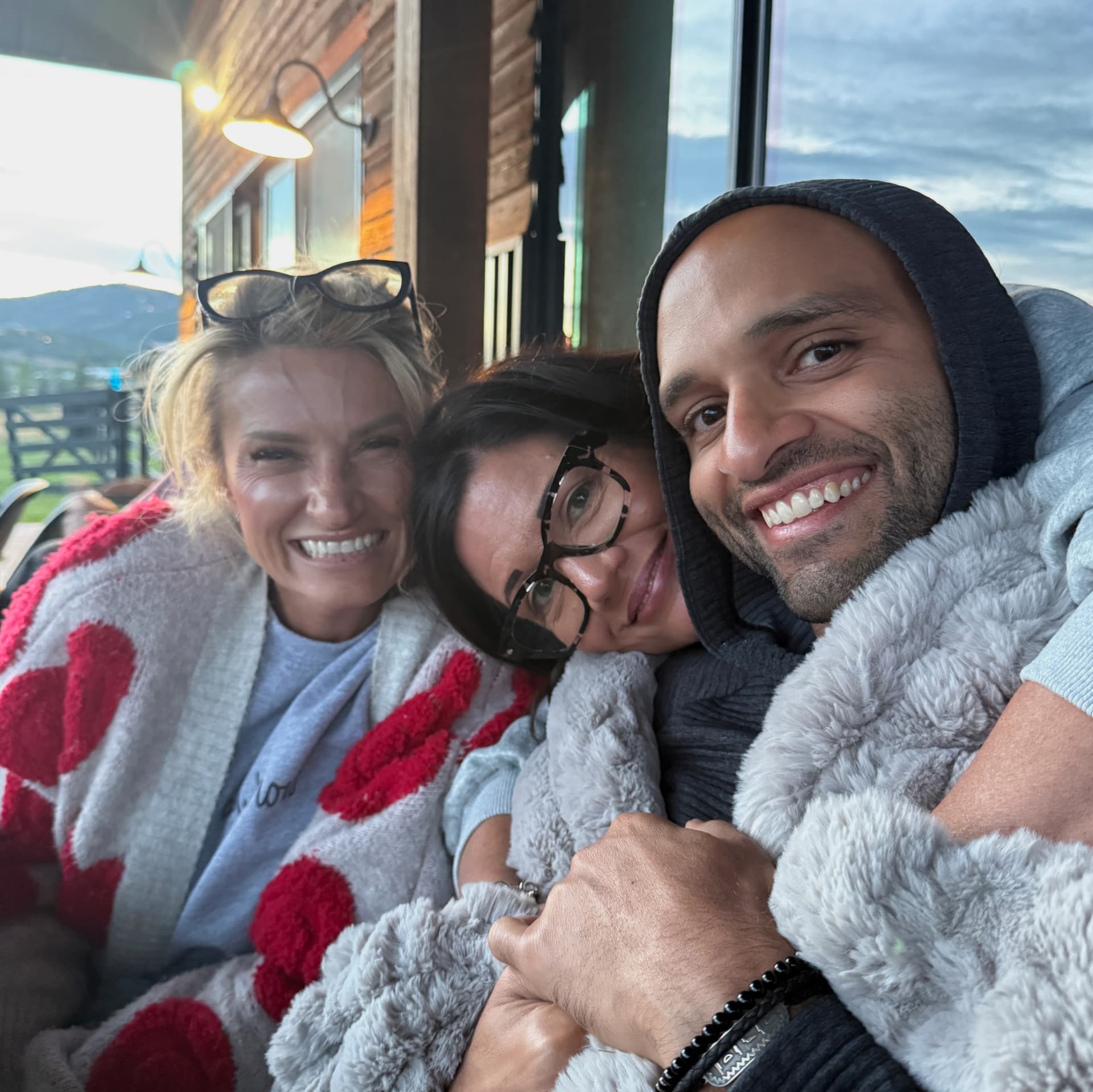 Three participants wrapped in blankets, smiling at dusk