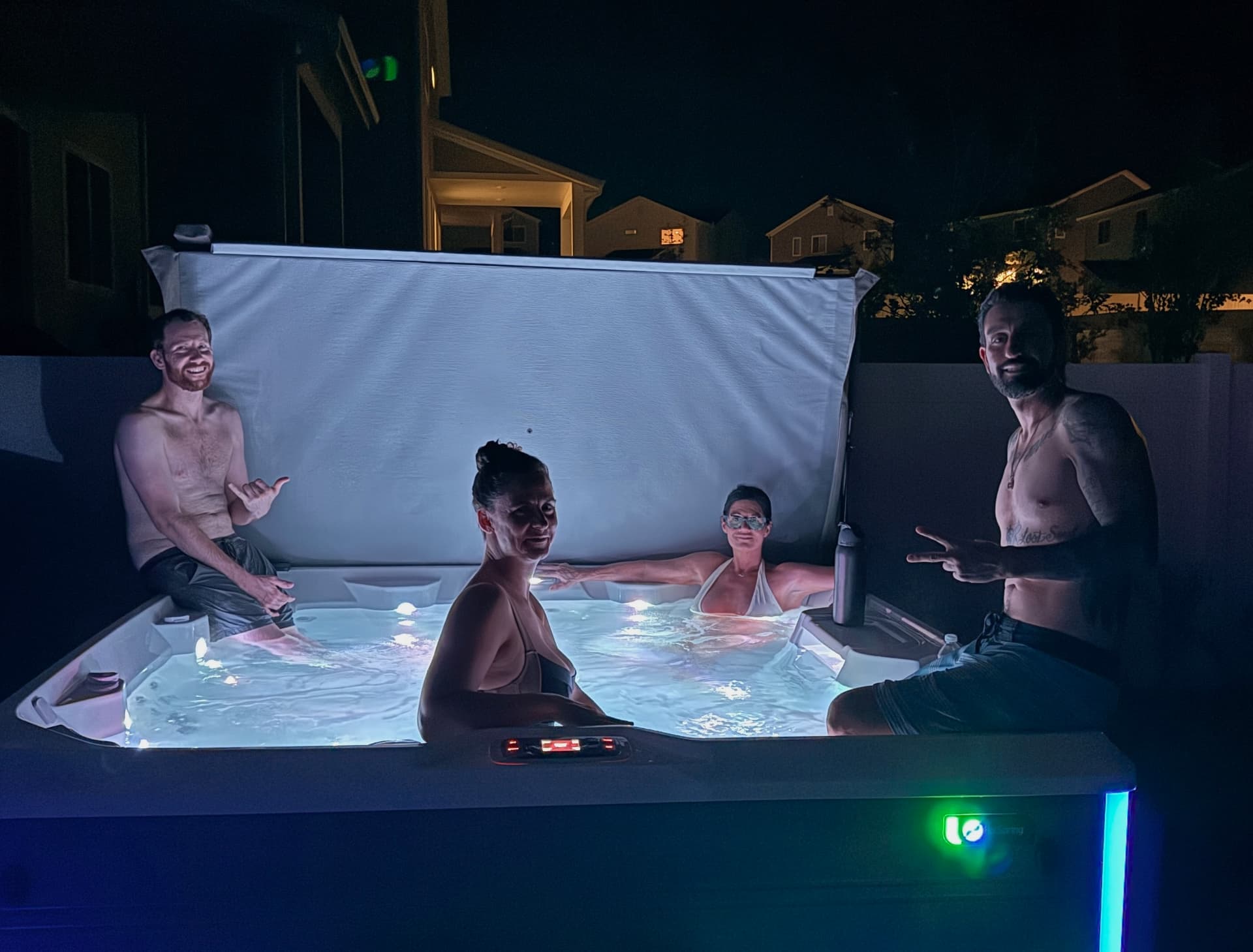 Four participants relaxing together in a lit hot tub after dark