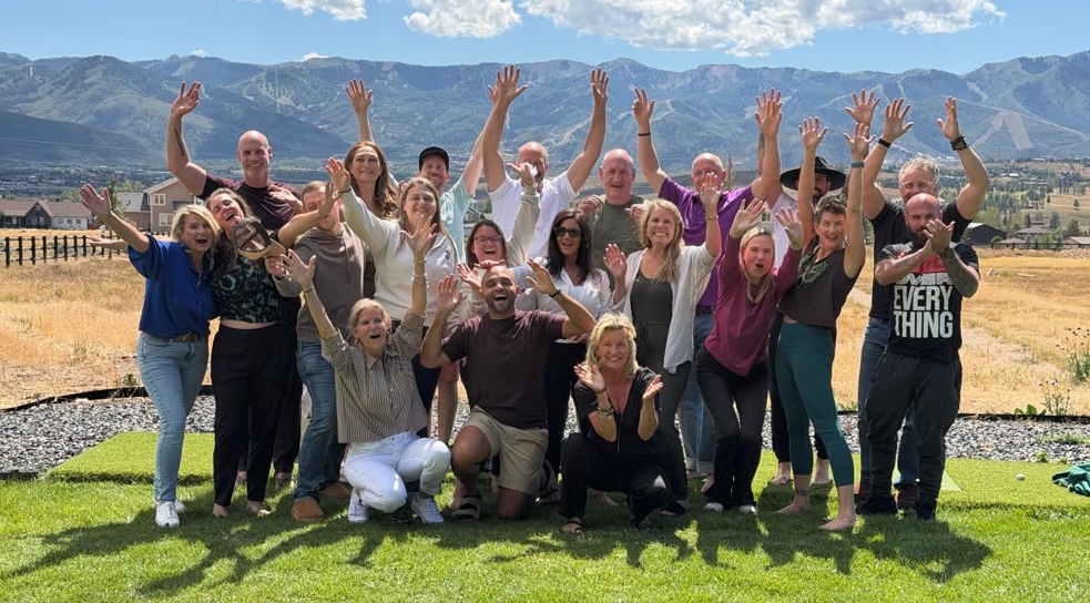The full retreat cohort raising their hands together with the Park City mountains behind